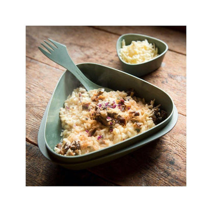 A Light My Fire Spork Original BIO in Deeply Blue rests in a bowl of risotto on a wooden table with a small bowl of cheese nearby.