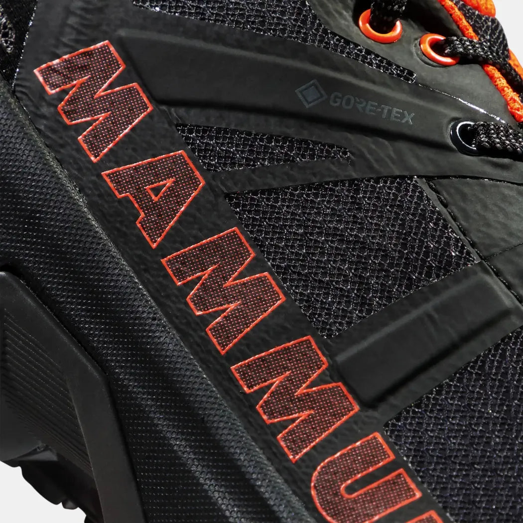 A close-up side view of the Mammut Sertig II Low GTX Men's shoe in Black-Vibrant Orange showing the mesh upper and Gore-Tex branding.