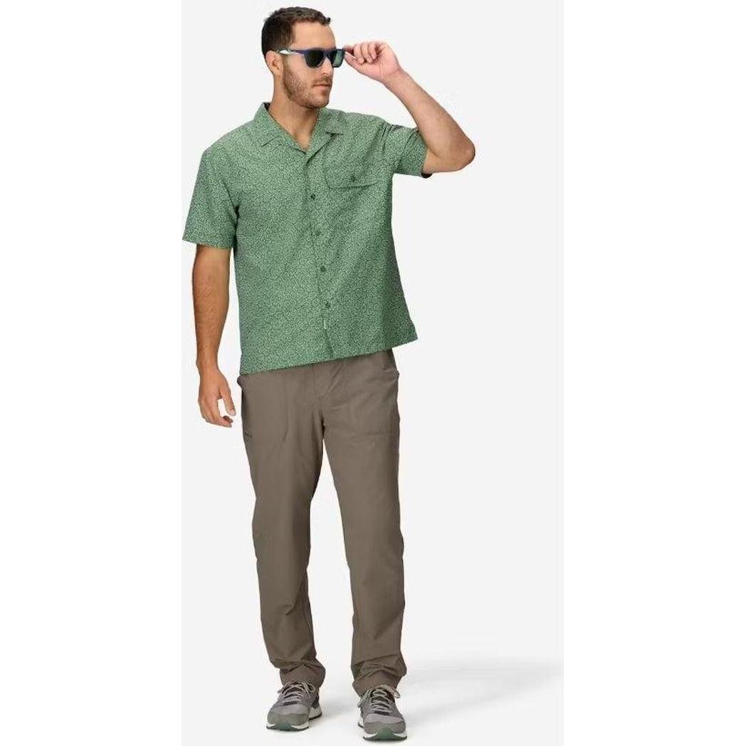 A man wearing the Marmot Men's AirExchange SolarShield Camp Novelty SS Shirt in Juniper Green Mini Bloom stands against a white background.