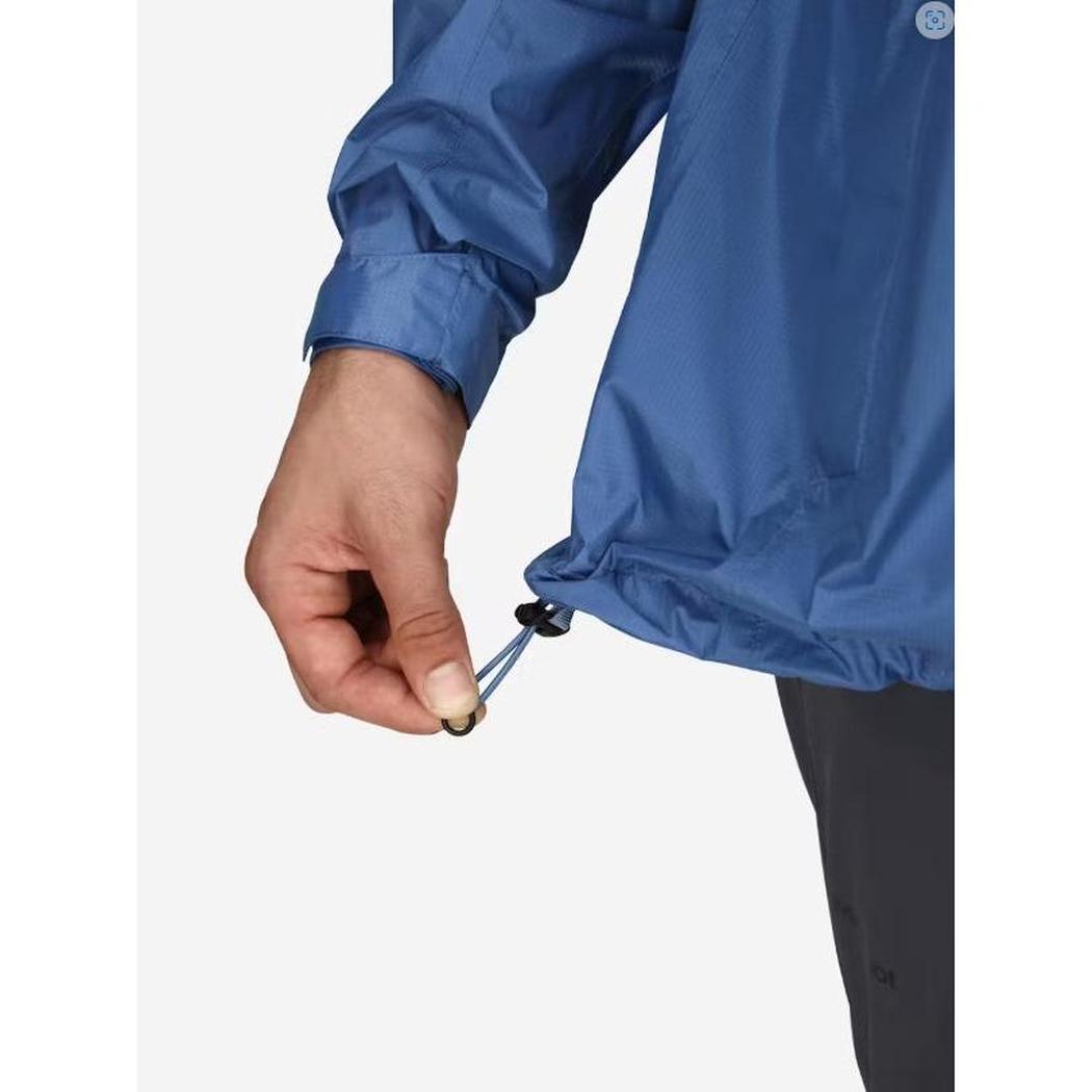 A close-up of the Marmot Men's PreCip Eco Jacket in Arctic Navy showing the adjustable hem cord and a model's hand holding it against a plain white background.