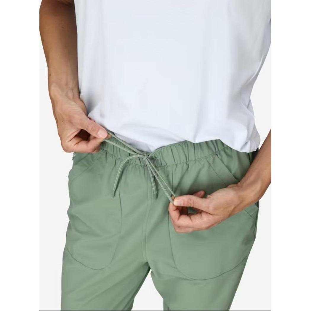 A model wearing the Marmot Women's AirExchange SolarShield Jogger in Agate Green adjusts the drawstring against a plain white background.