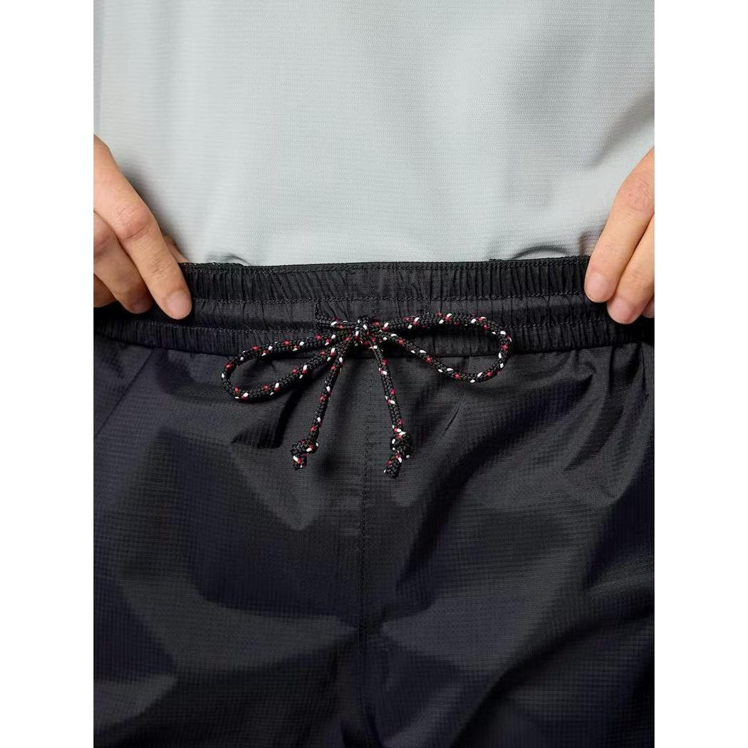 A close-up of the Marmot Women's PreCip Evo Pant in Black, showing the elastic waistband and drawstring against a light gray shirt.