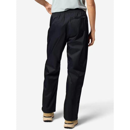 Back view of the Marmot Women's PreCip Evo Pant in Black on a model wearing light-colored shoes against a plain white background.