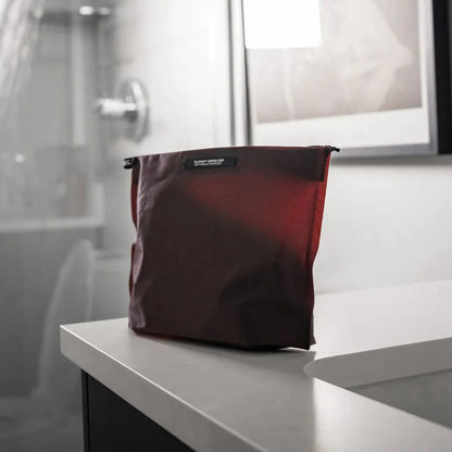 A flat, zippered Matador FlatPak toiletry case in Arctic White sits on a white countertop with a bathroom background.