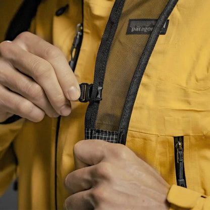A close-up of a person adjusting the straps on a black Matador Freefly 16 Packable Backpack.
