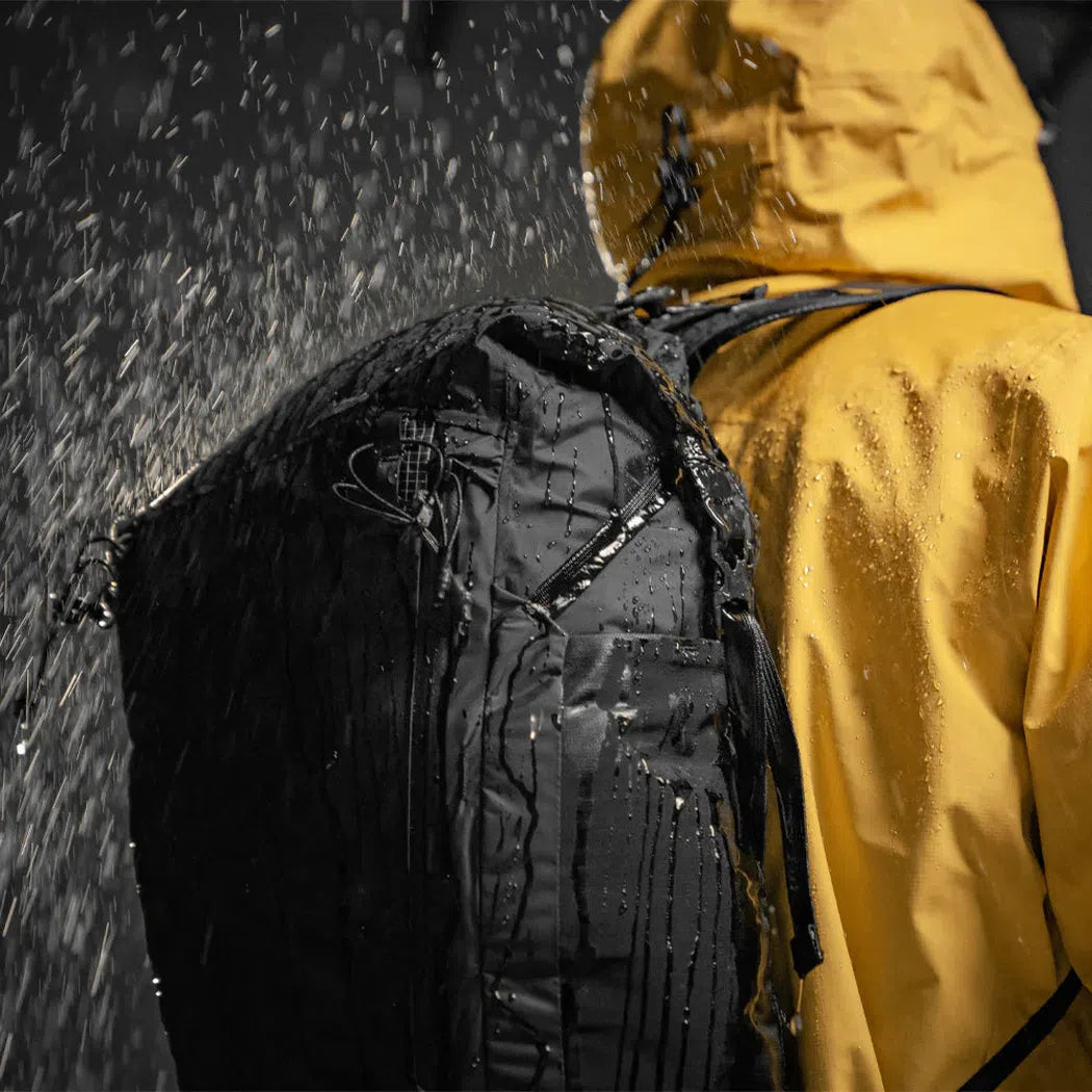 Back view of the Matador Freerain 22 Waterproof Packable Backpack in Black with water droplets on the pack and jacket in the rain.