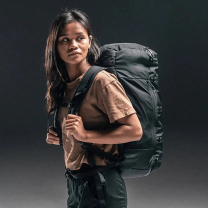 A woman wearing the Matador SEG 45 Travel Pack in Black stands against a dark background.