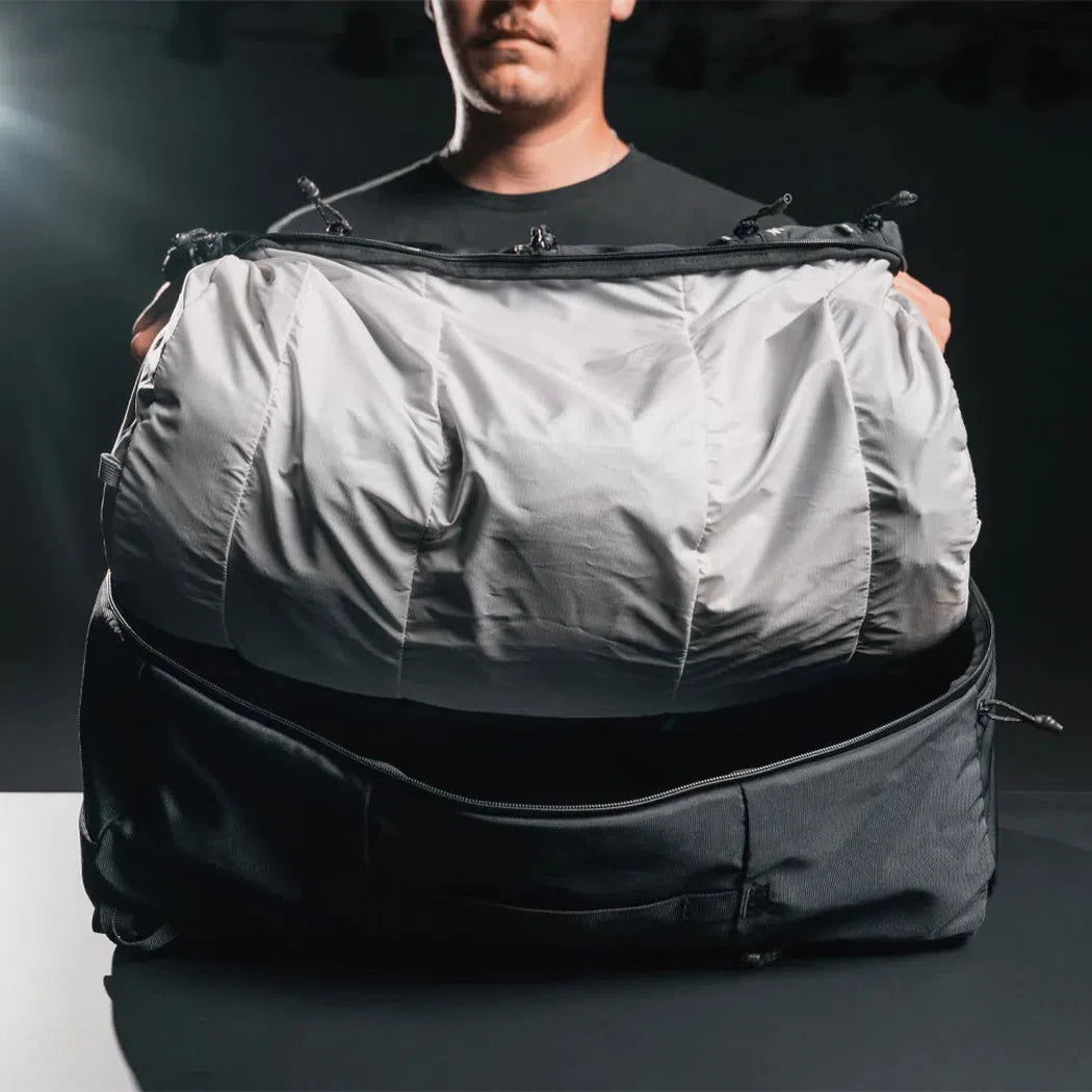 A man holds the Matador SEG 45 Travel Pack open to show its spacious interior against a dark background.