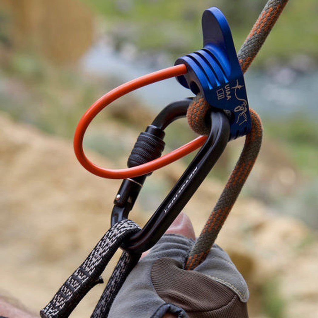 A close-up of the Metolius Element II Screw Lock carabiner in Black attached to a climbing rope with a gloved hand visible.