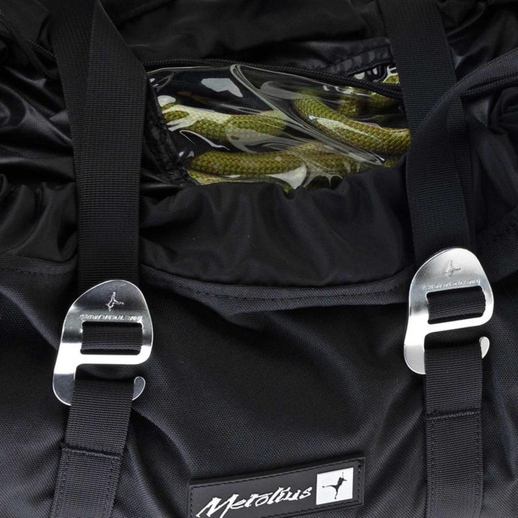 A close-up of the Metolius Rope Master HC rope bag in Rust showing the metal buckles and a green rope inside.