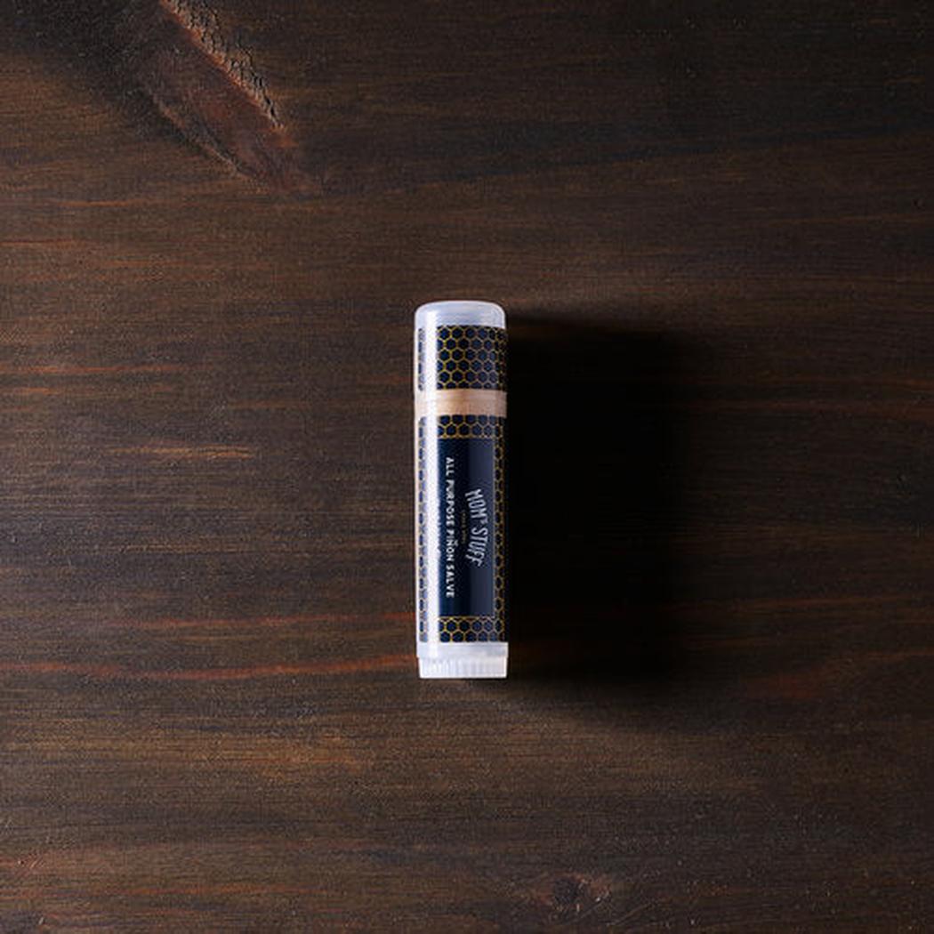 A top-down view of the Moms Stuff Salve All Purpose Pinon Salve - Large Tube on a dark wooden surface.