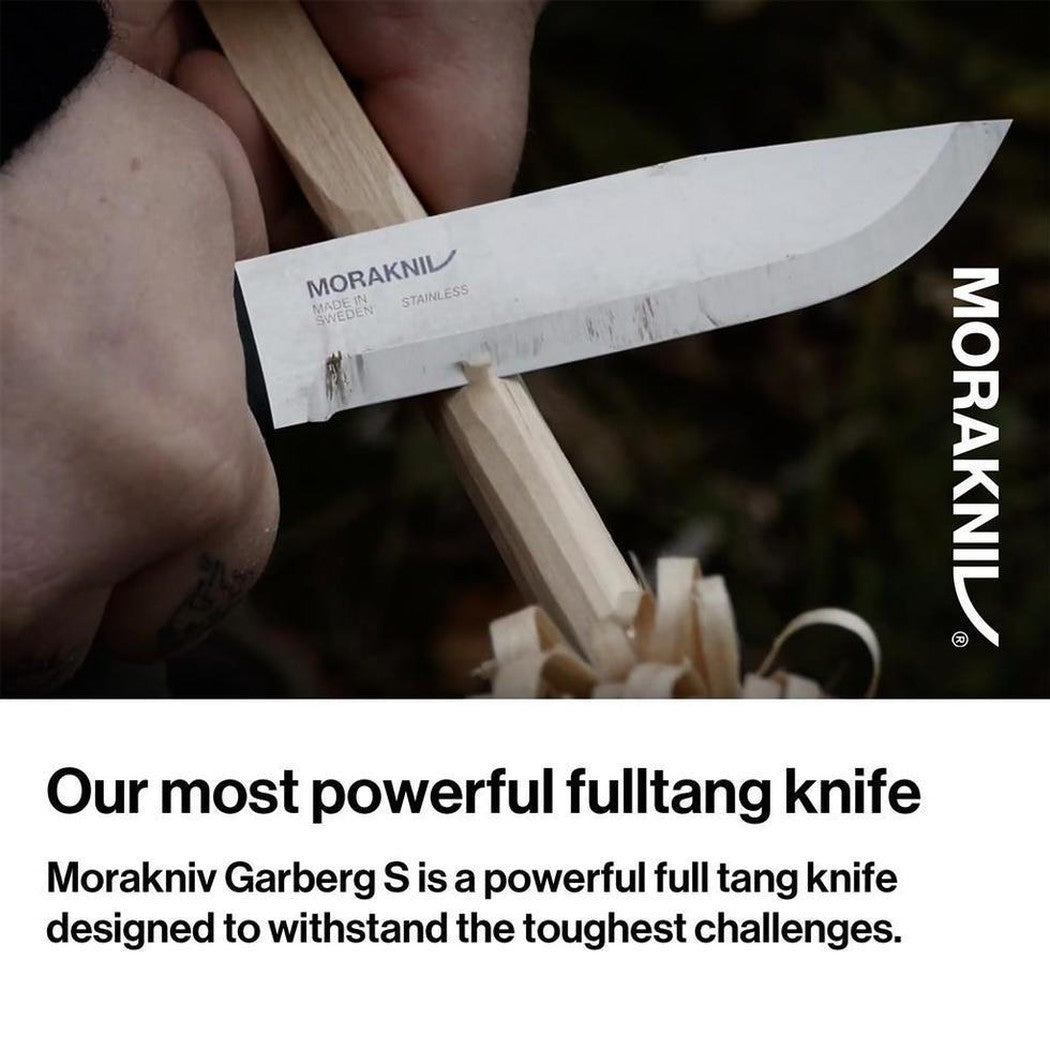 A hand holds the Morakniv Garberg Stainless Steel Knife with a wooden handle, showing the blade cutting wood shavings in a close-up shot.