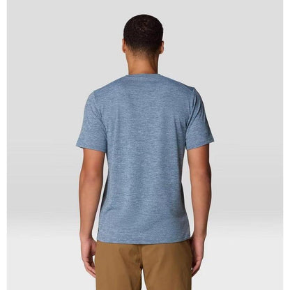 Back view of the Mountain Hardwear Men's Sunblocker Short Sleeve in Adriatic Blue Heather on a model wearing khaki pants against a light gray background.