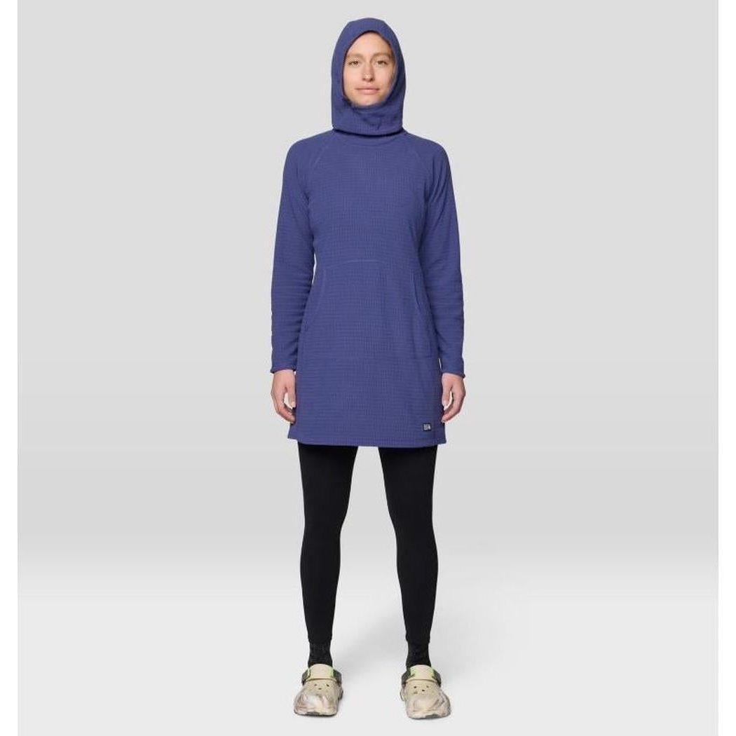 A front view of the Mountain Hardwear Women's Summit Grid Dress in Bourbon Brown on a model wearing black leggings and light-colored shoes against a plain background.