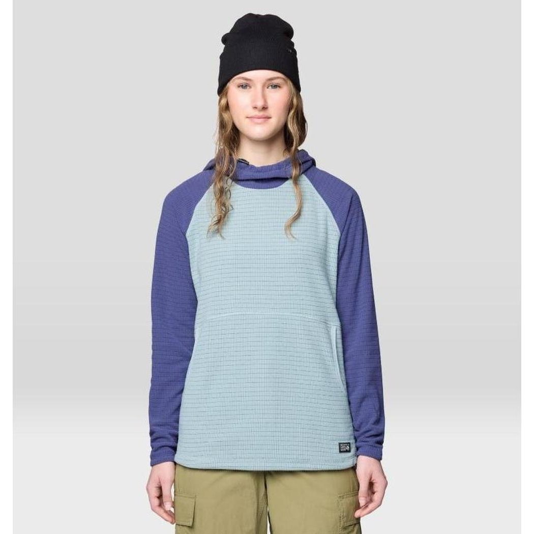A woman wearing the Mountain Hardwear Women's Summit Grid Tunic Hoody in Ice Shadow/Lapis Dusk stands against a light gray background.