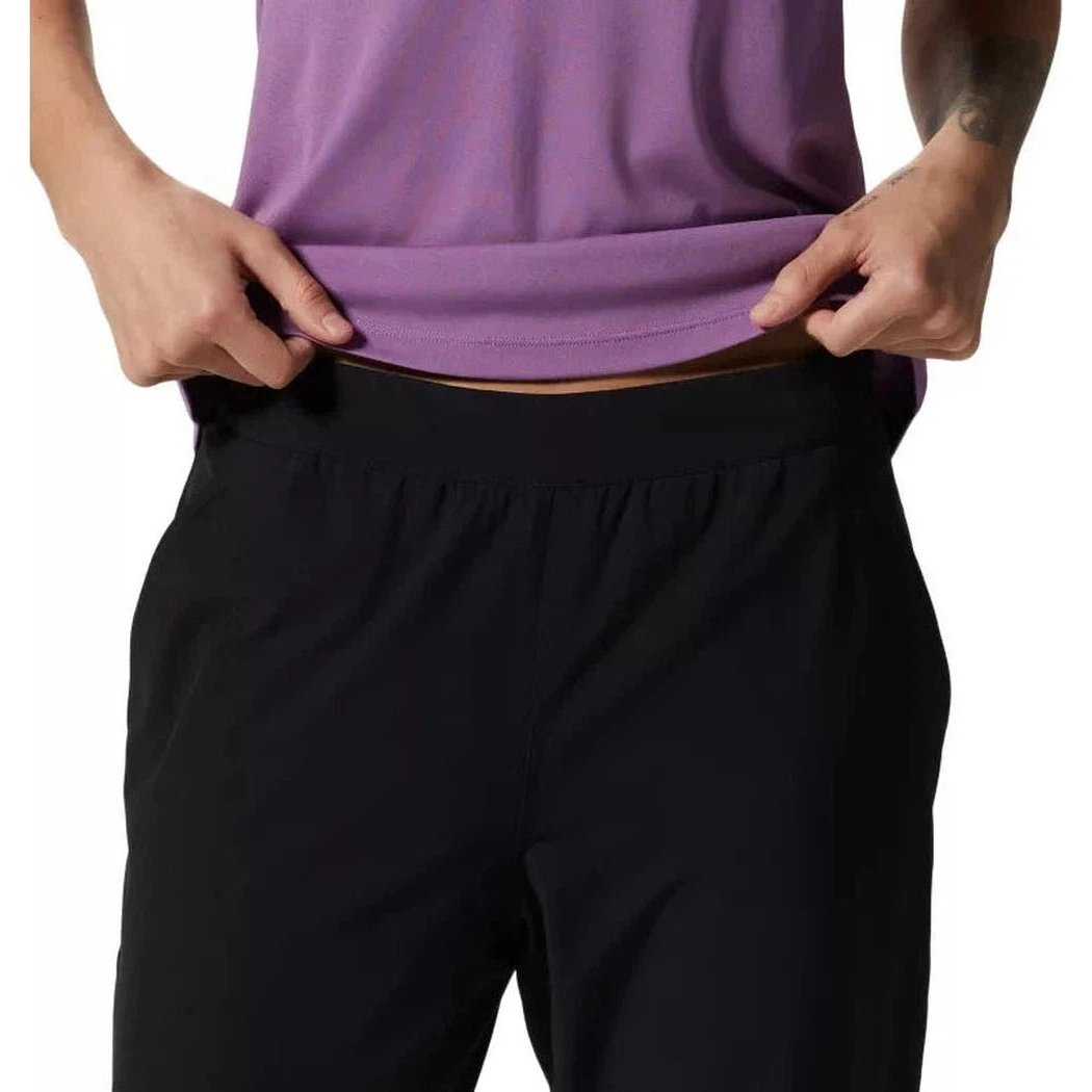 A model wearing the Mountain Hardwear Women's Yumalina Active Pull-On Lined Jogger in Black pulls up their purple top to show the waistband.
