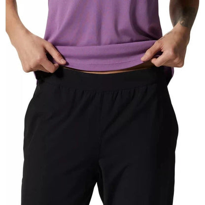 A model wearing the Mountain Hardwear Women's Yumalina Active Pull-On Lined Jogger in Black pulls up their purple top to show the waistband.