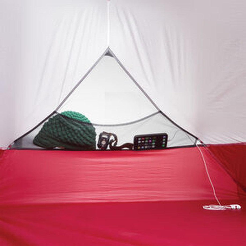 A red MSR Hubba Hubba 2 Tent V9 with a green sleeping bag and a phone visible inside.