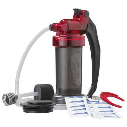 A front view of the MSR MiniWorks EX Purifier System with its red and black handle, charcoal filter, and cleaning packets on a white background.