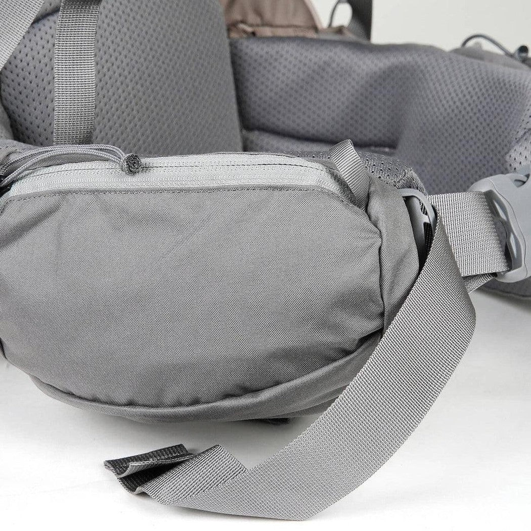 A front view of the Mystery Ranch Backpacks Women's Coulee 50 in Pebble showing the waist strap and zipper pocket against a white background.