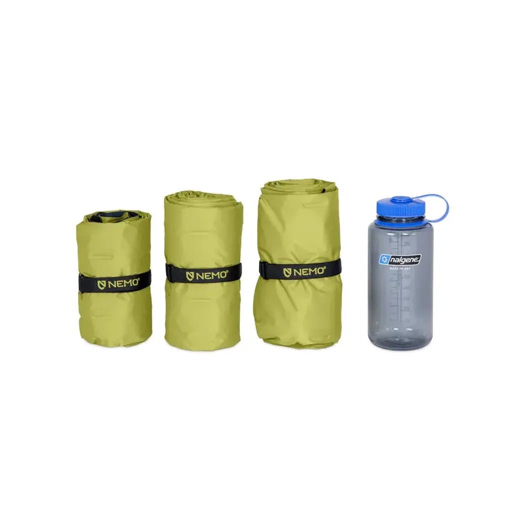Three rolled NEMO sleeping pads and a gray Halogen water bottle on a white background.