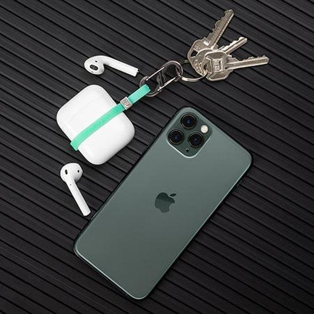 A black Nite Ize Cinch-A-Lot Mini Stretch Strap with a carabiner holding keys and earbuds, laid on a dark textured surface.