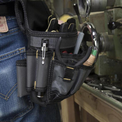 A close-up of the Nite Ize Inova XP LED Pen Light in a black tool pouch attached to blue jeans, with a workshop background.