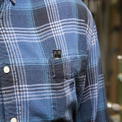 A close-up of the Nite Ize Inova XP LED Pen Light clipped to the chest pocket of a blue plaid flannel shirt.