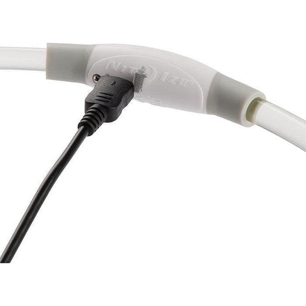 A close-up of the Nite Ize Nitehowl Led Safety Necklace Rechargeable with a black charging cable plugged in, against a white background.
