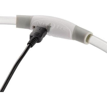 A close-up of the Nite Ize Nitehowl Led Safety Necklace Rechargeable with a black charging cable plugged in, against a white background.