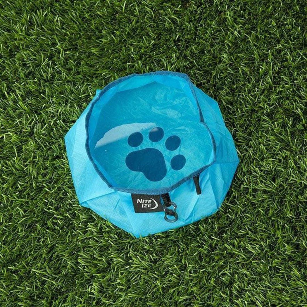 A blue Nite Ize Raddog Collapsible Bowl sits on green grass from a top-down angle.