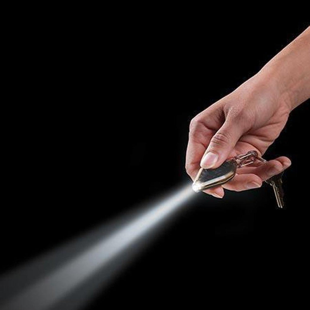 A hand holds the Nite Ize Radiant Rechargeable Microlight, which emits a bright beam against a black background.