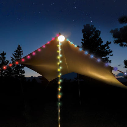 A golden tarp with colorful string lights and a glowing lantern pole stands under a starry night sky with trees in the background.