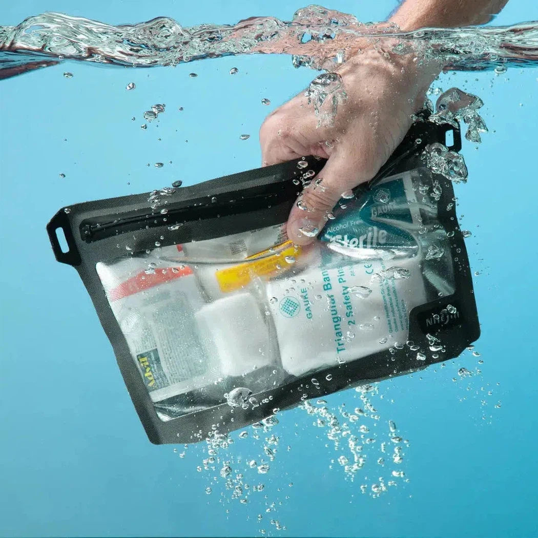 A hand holds the Nite Ize RunOff Waterproof 3-3-1 Pouch underwater with clear blue water in the background.
