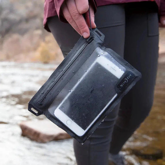 A person holds the Nite Ize RunOff Waterproof Pocket with a phone inside, against a rocky outdoor background.