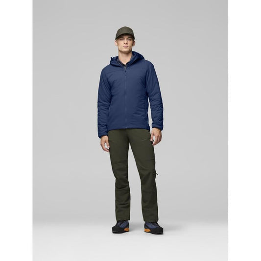 A model wearing the Norrona Men's Femund Thermo60 Zip Hood in Indigo Night stands against a light gray background.