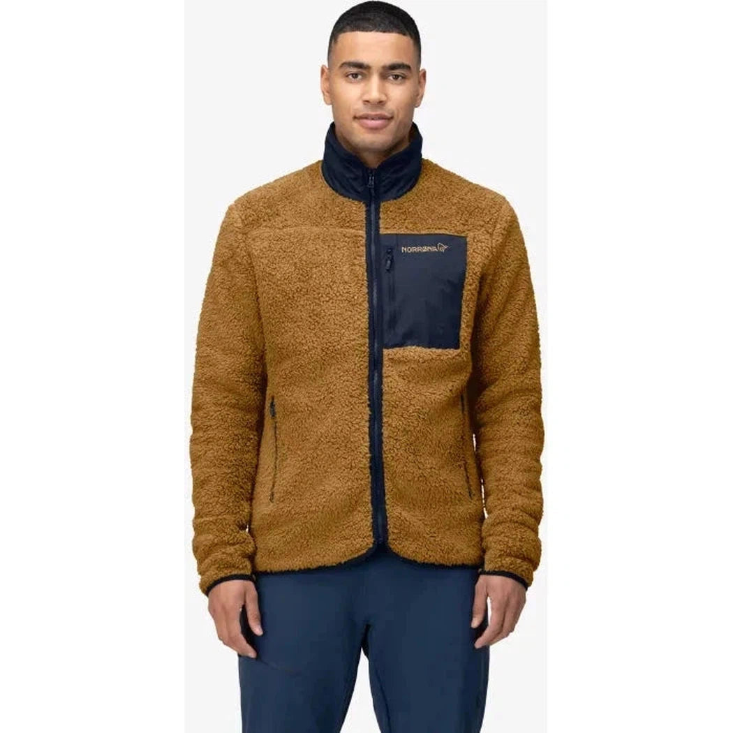 A front view of the Norrona Men's Femund Warm3 Jacket in Camelflage with a dark blue chest pocket and collar, on a model wearing dark blue pants against a white background.