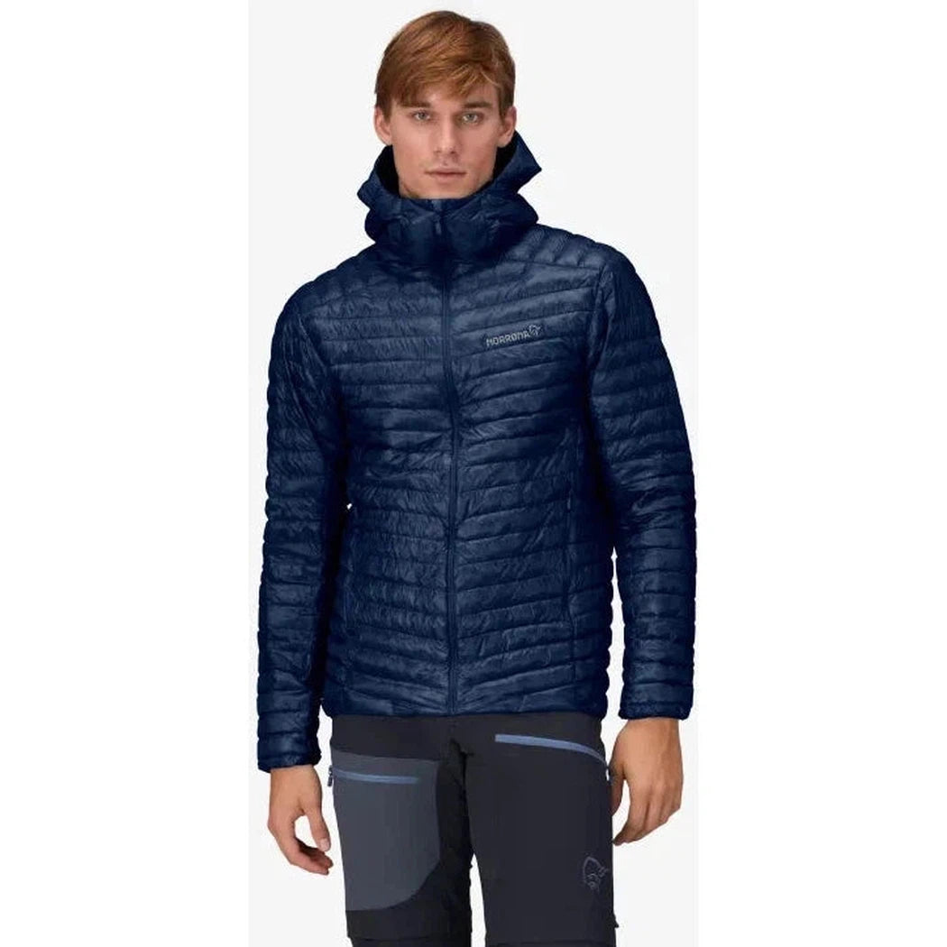 A front view of the Norrona Men's Trollveggen Superlight Down800 Hood in Indigo Night on a model wearing dark pants against a white background.