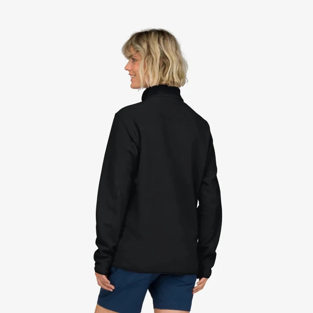 Back view of the Norrona Unisex Femund Warm 2 Halfzip in Caviar Black on a model wearing blue shorts against a white background.
