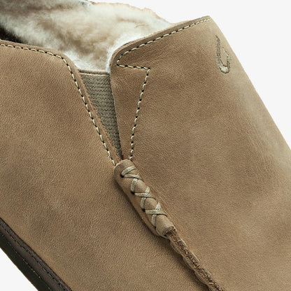 A close-up of the Olukai Men's Moloa Slipper in Clay/Dark Java showing the lace detail and shearling lining against a white background.