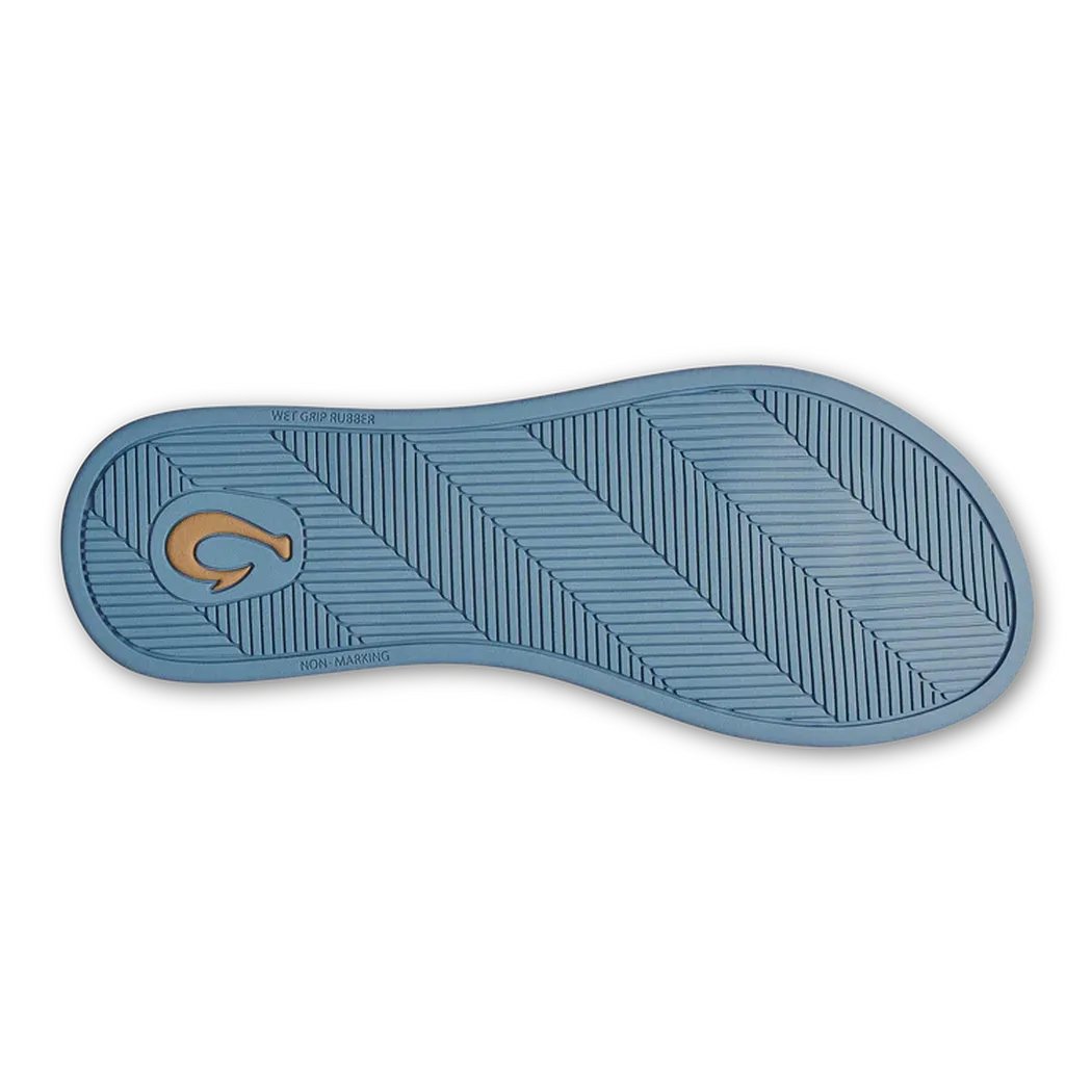 The sole of the Olukai Women's ‘Uiki Bright Sky sandal is shown from above, displaying the textured tread pattern and a small logo on a white background.