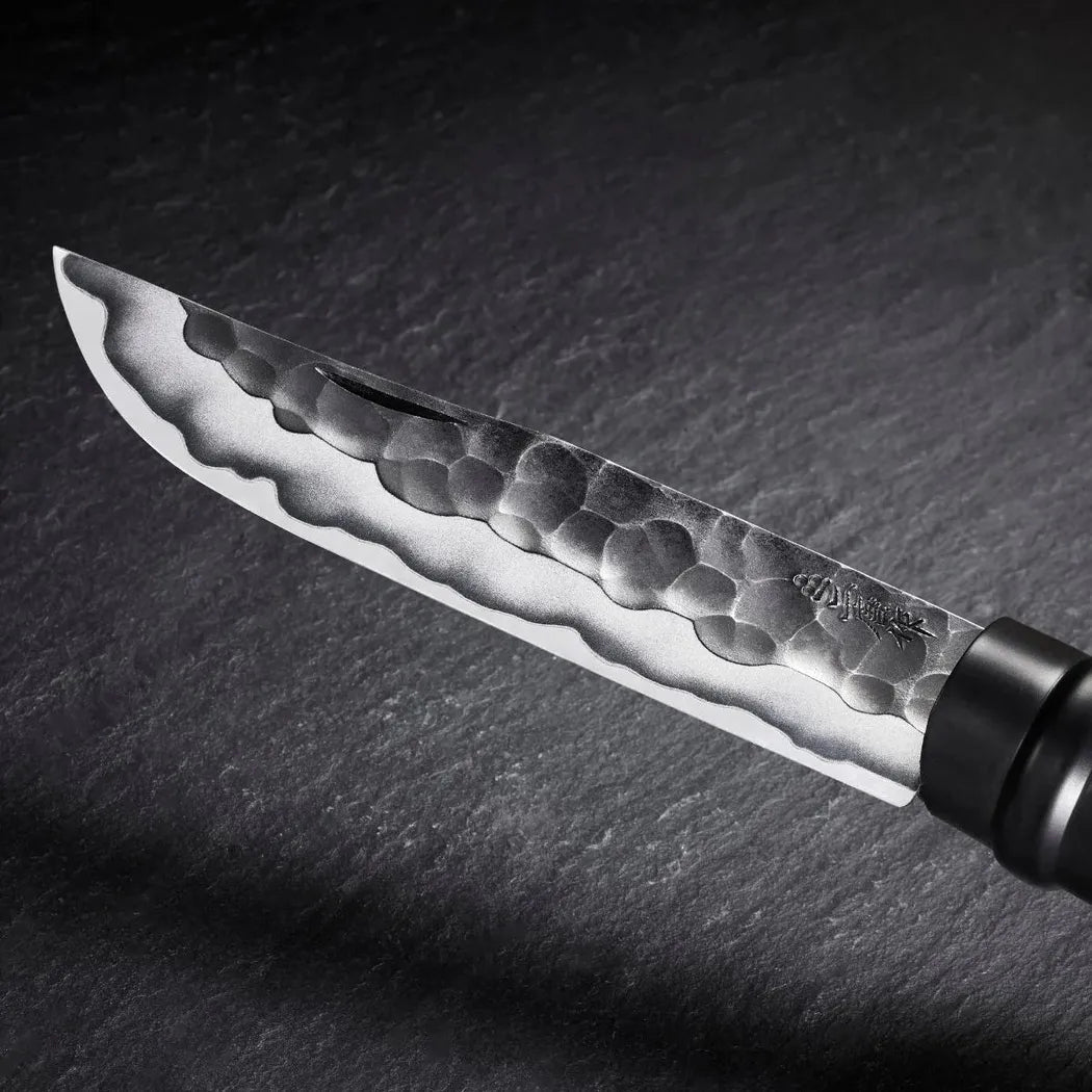 A close-up of the Opinel Limited Edition No.10 Shiori knife with a hammered blade, black handle, and dark slate background.
