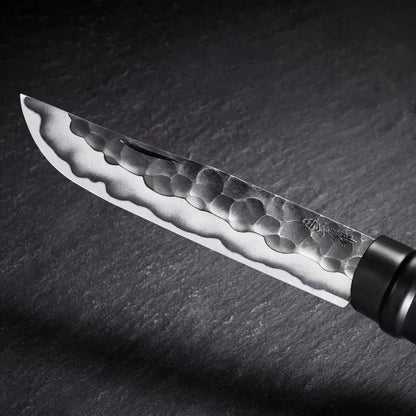 A close-up of the Opinel Limited Edition No.10 Shiori knife with a hammered blade, black handle, and dark slate background.