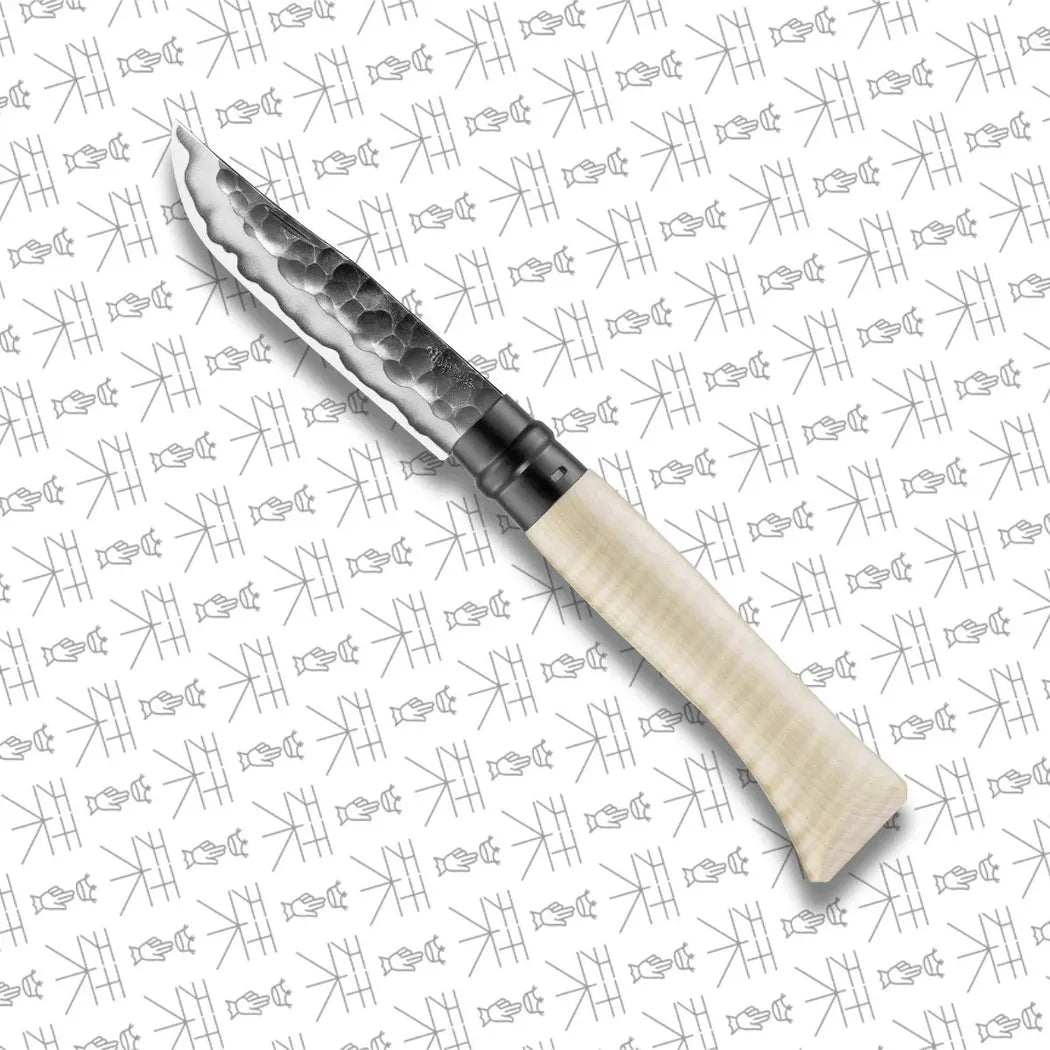 A side view of the Opinel Limited Edition No.10 Shiori knife with a hammered blade and light-colored handle against a patterned background.