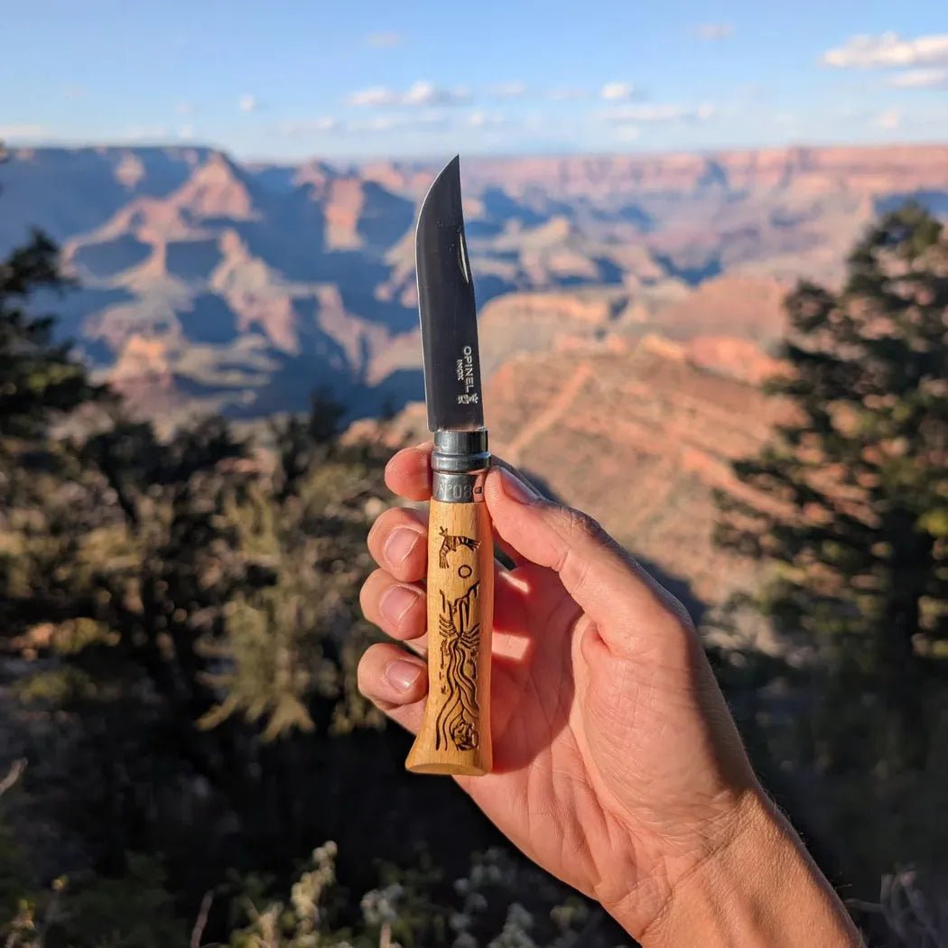 A hand holds the Opinel National Parks Collection Grand Canyon knife with the Grand Canyon landscape in the background.