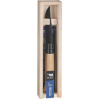 A natural wood box holds the Opinel No.08 Black Oak folding knife with its black blade and wooden handle visible.