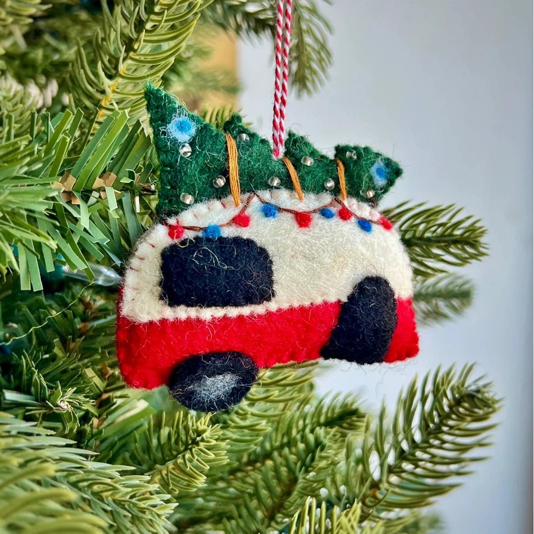 A close-up of the Ornaments 4 Orphans Camper Felt Wool Christmas Ornament hanging on a green Christmas tree branch.