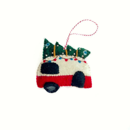 A felt Christmas ornament shaped like a red and white camper with a green tree on top, hanging from a red and white string.