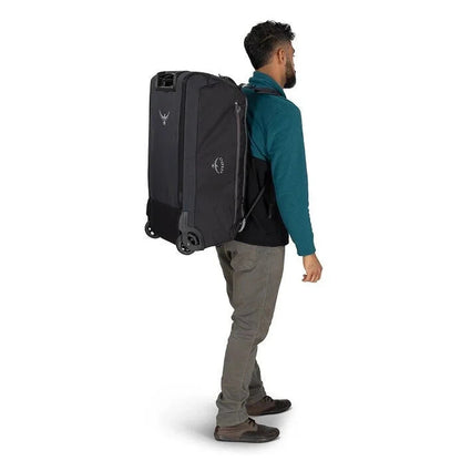 Side view of the Osprey Daylite Wheeled Duffel 85 in Black on a man against a white background.