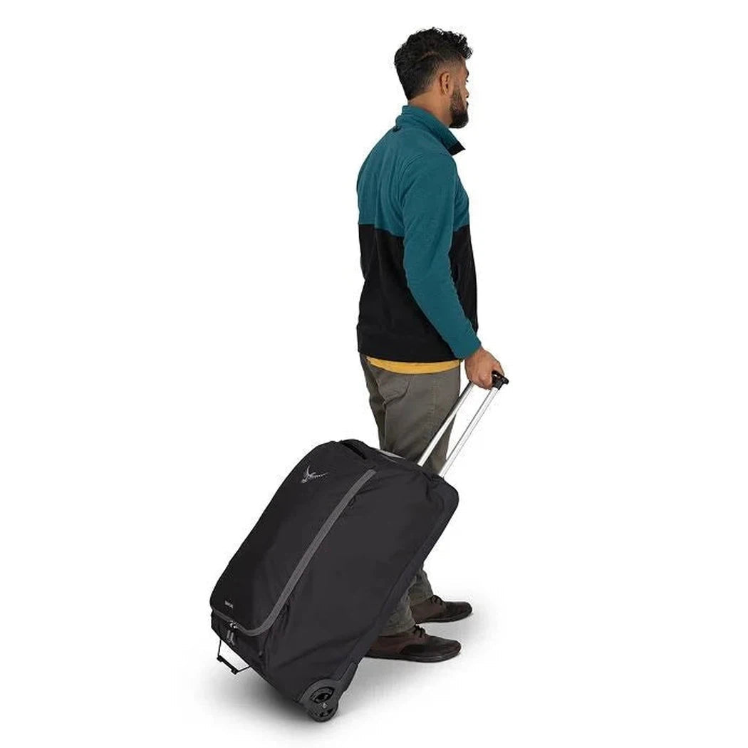 Side view of the Osprey Daylite Wheeled Duffel 85 in Black showing the telescoping handle and wheels against a white background.